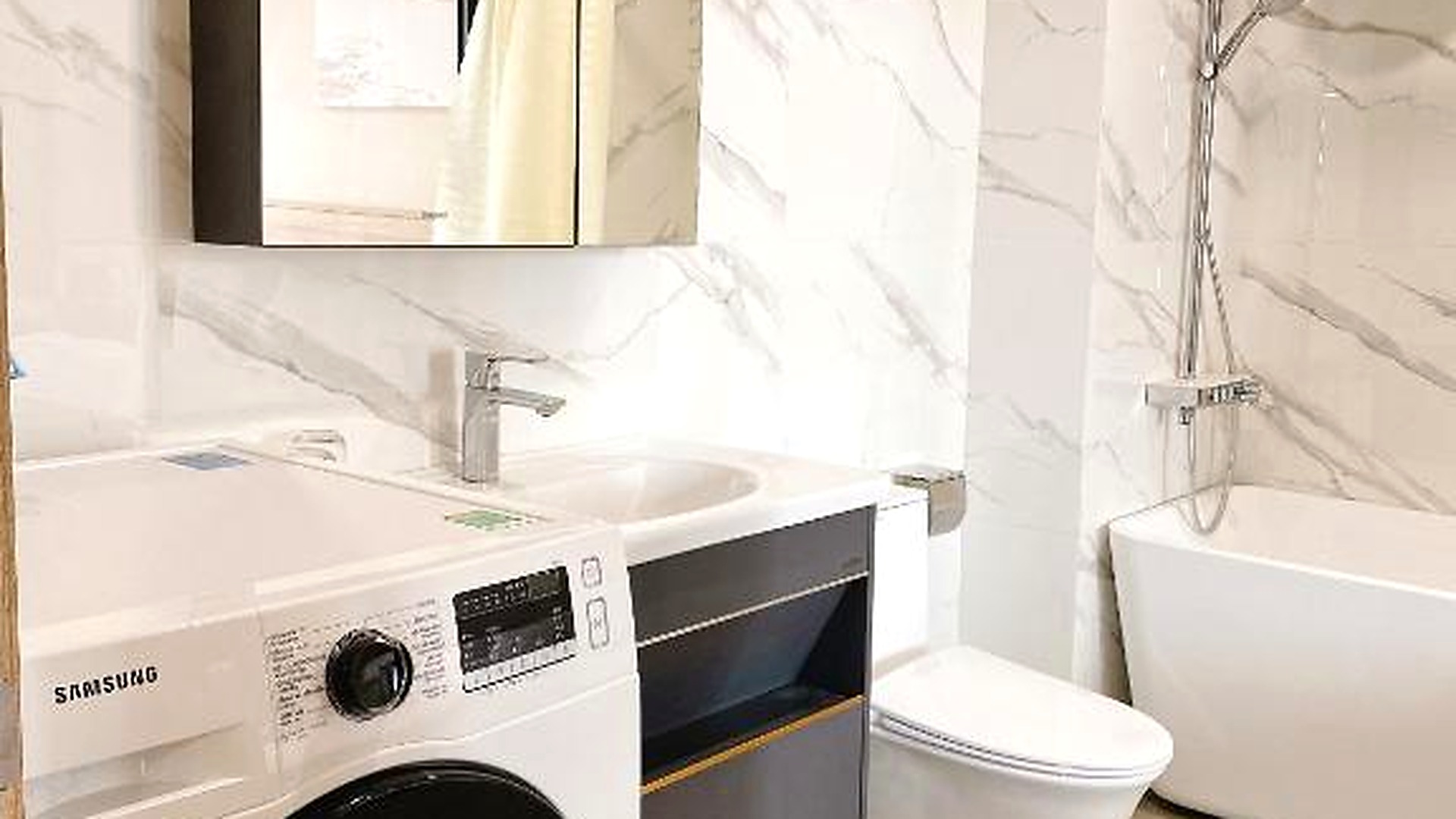 Phòng tắm khách sạn 4 sao tích hợp máy giặt, lavabo và khu tắm tiện nghi.