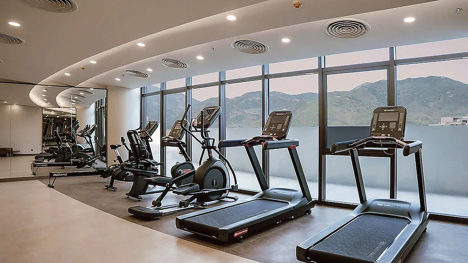 Phòng gym rộng thoáng với hệ máy cardio và tầm nhìn hướng núi.