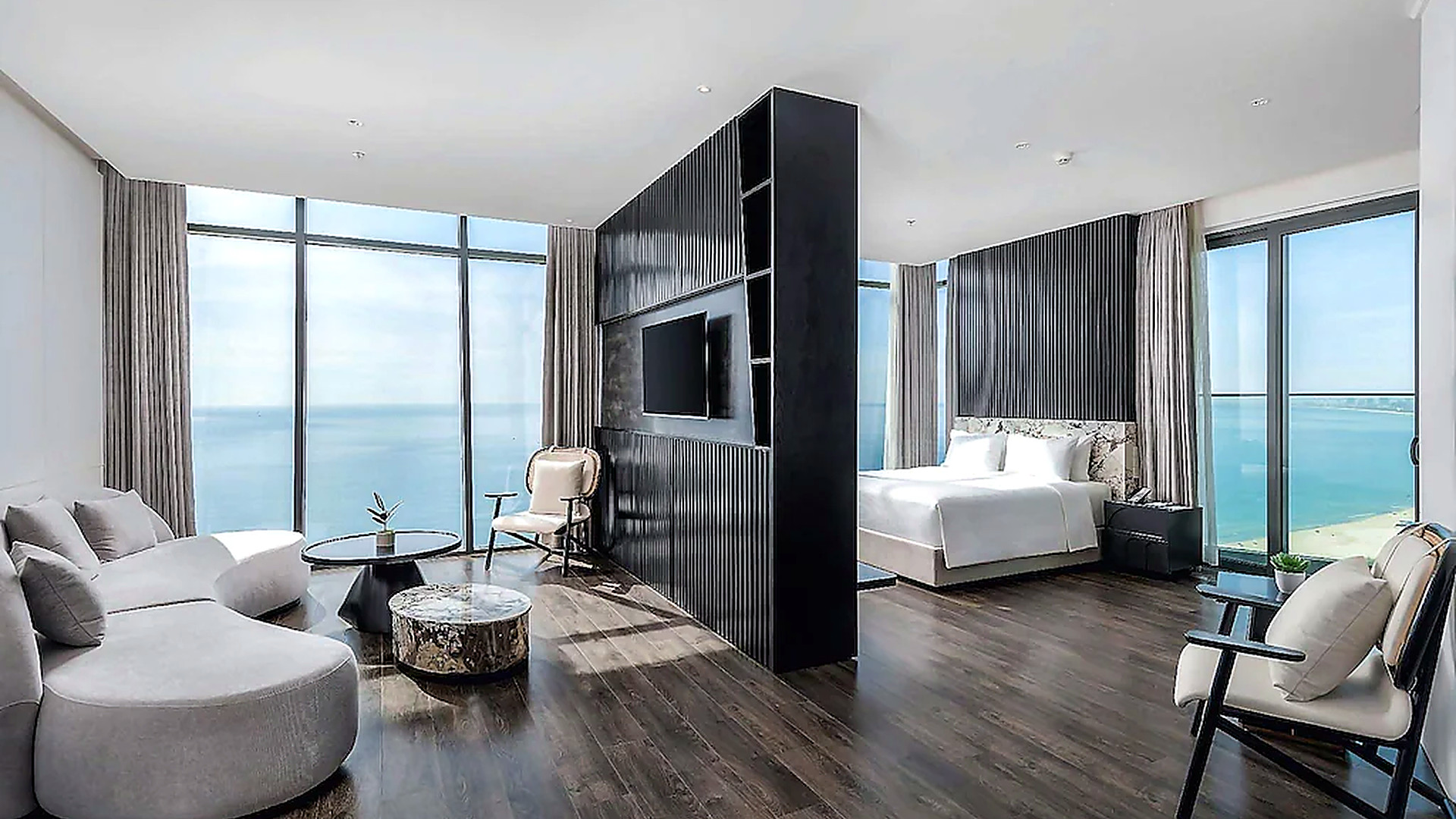 Phòng suite view biển với khu ngủ và khu tiếp khách được tổ chức mở, tận dụng cửa kính toàn cảnh.