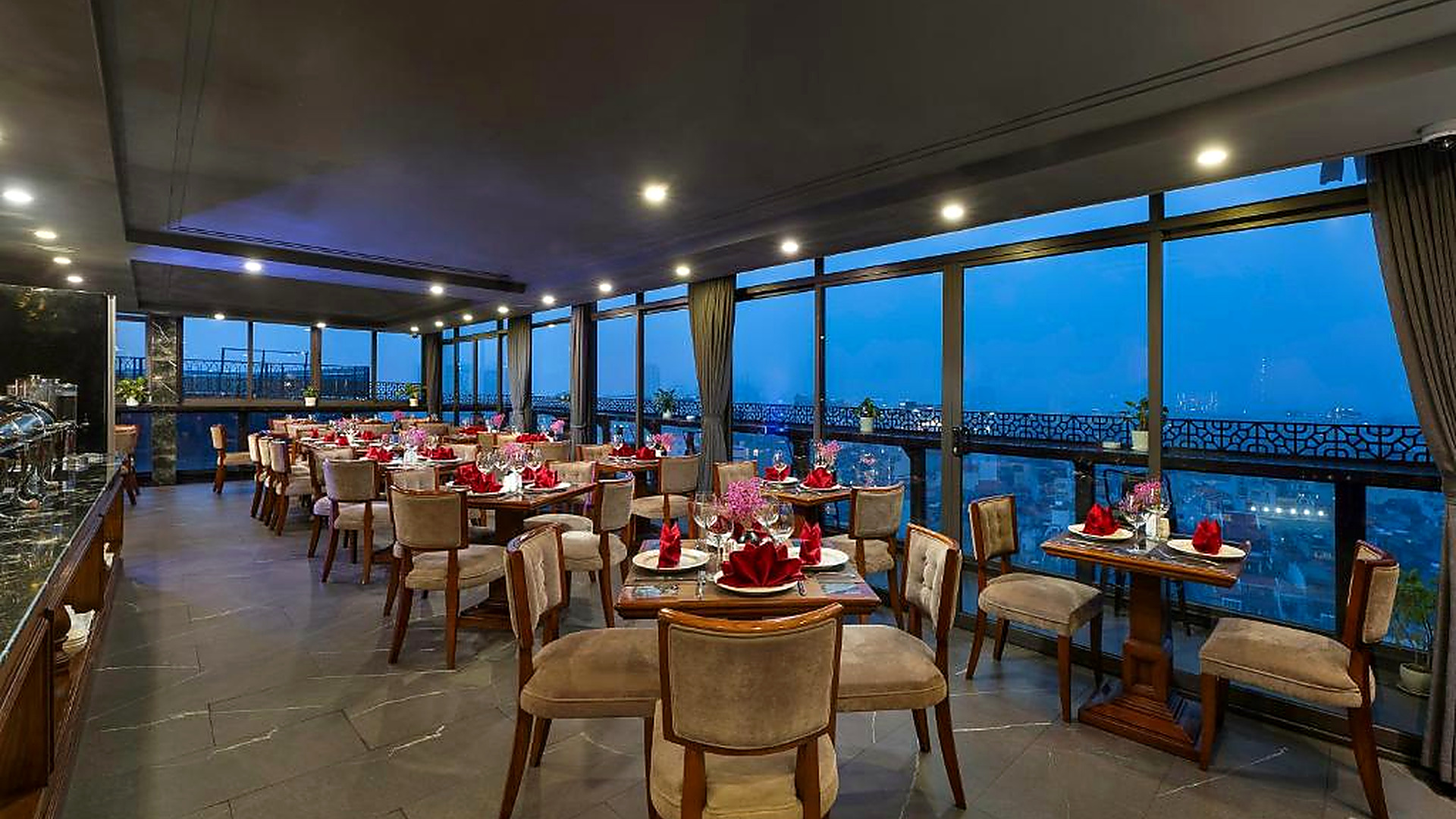 Nhà hàng rooftop vào buổi tối kết hợp view thành phố, bàn ăn chỉnh chu và không gian yên tĩnh.