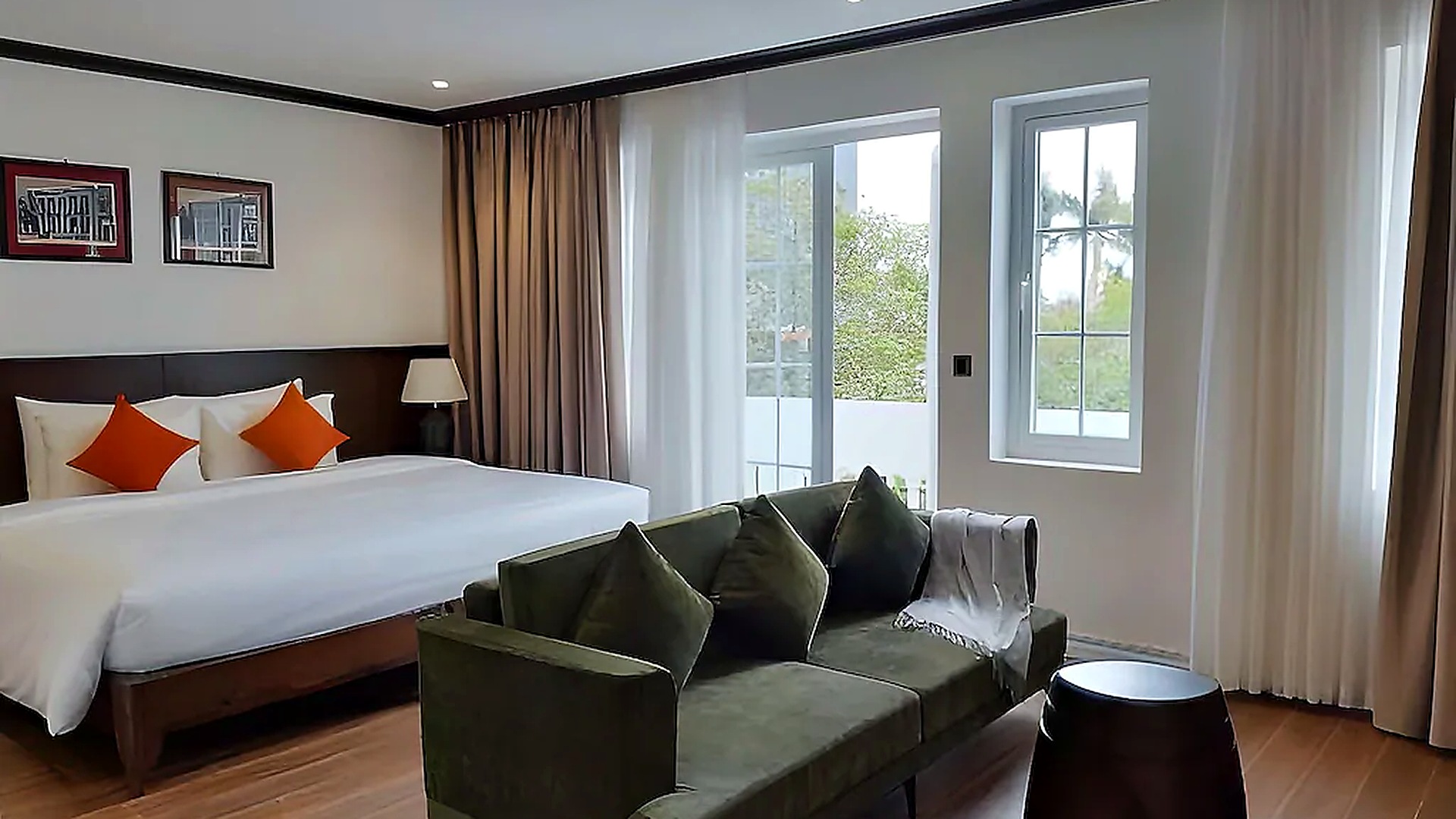 Phòng King khách sạn 4 sao với sofa xanh rêu và cửa sổ lớn.