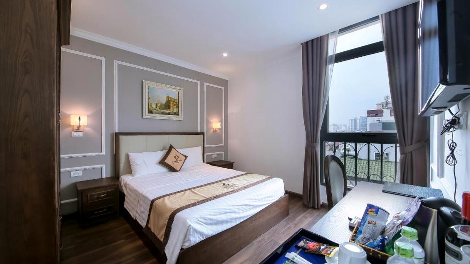 Nội thất phòng khách sạn dùng gỗ nâu và tường sáng để tạo cảm giác ấm, sạch, dễ bảo trì.
