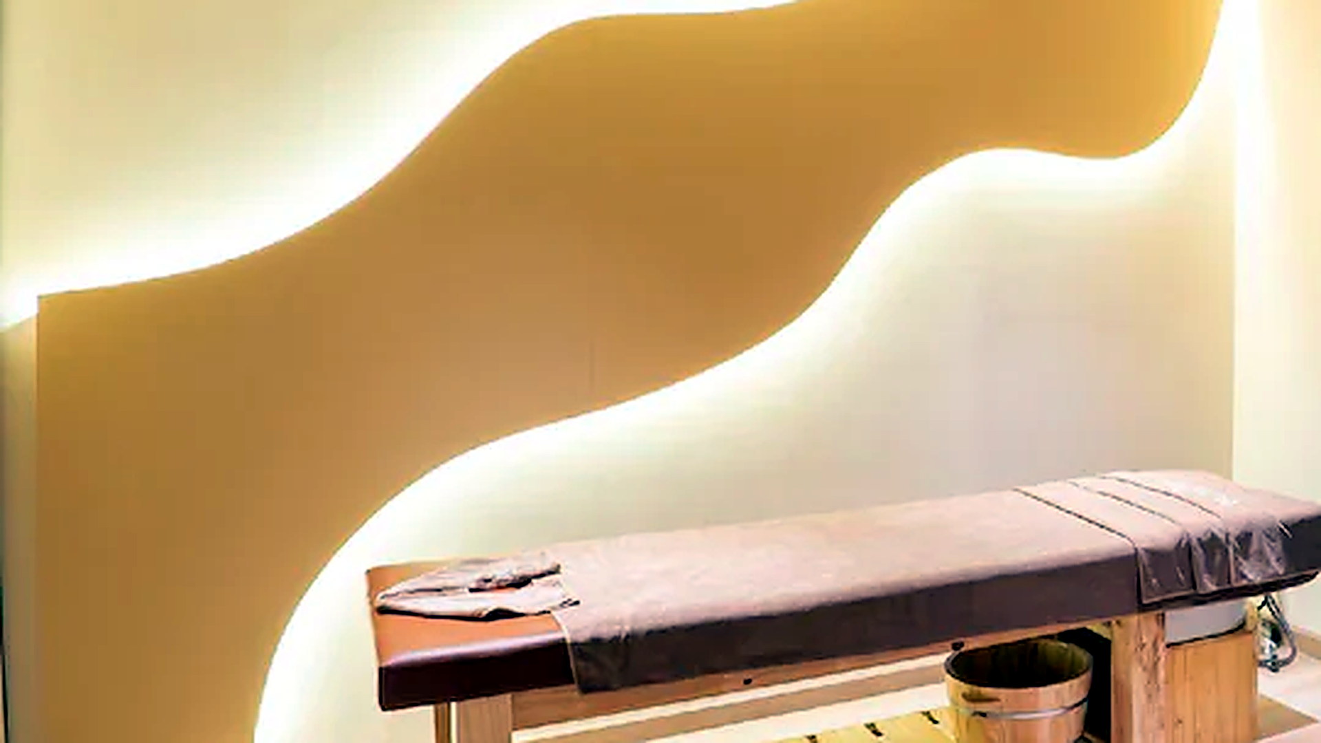 Phòng trị liệu spa sau khi loại bỏ người, giữ lại bố cục giường massage và mảng tường ánh sáng.