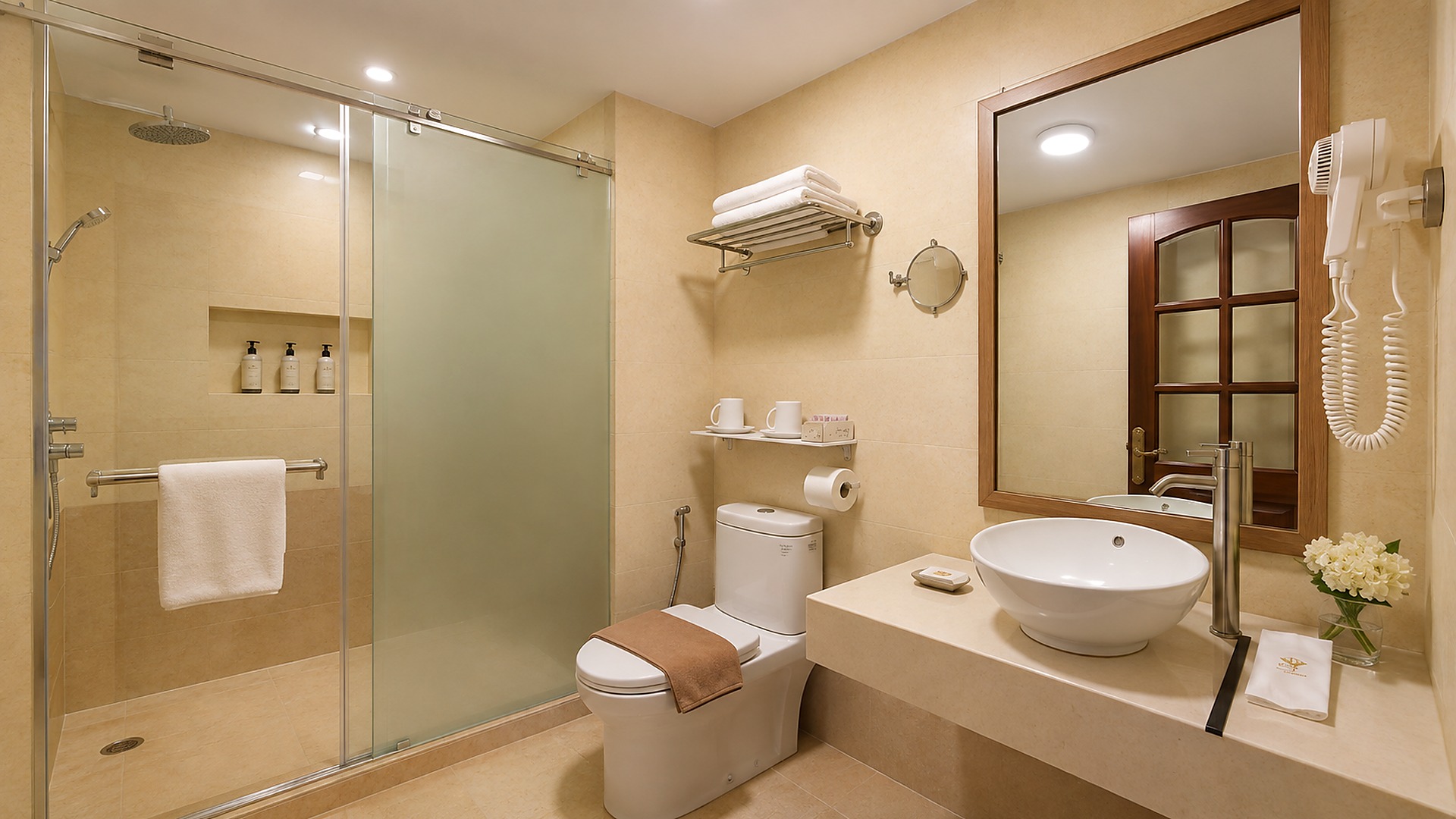 Phòng tắm khách sạn 4 sao với khu tắm kính, lavabo và hệ khăn gọn gàng.