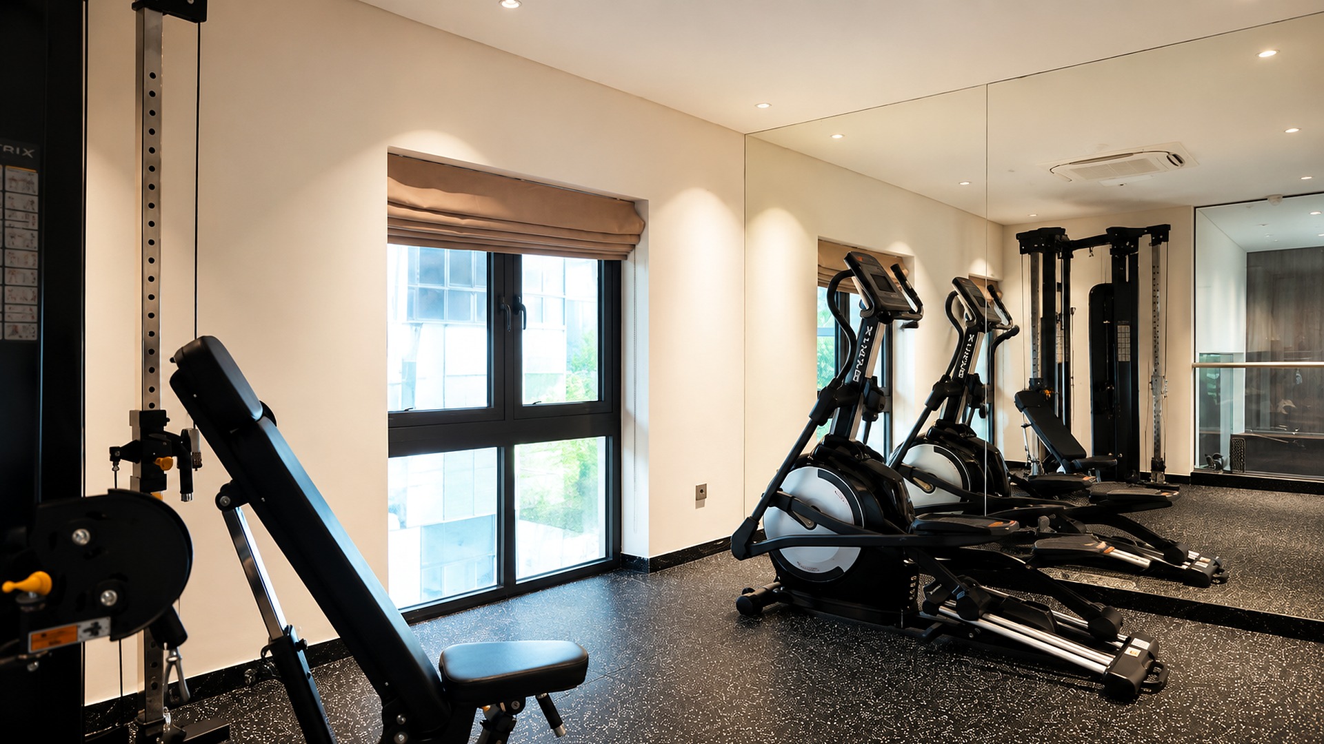 Phòng gym khách sạn 4 sao với thiết bị tập luyện hiện đại và hệ gương lớn.