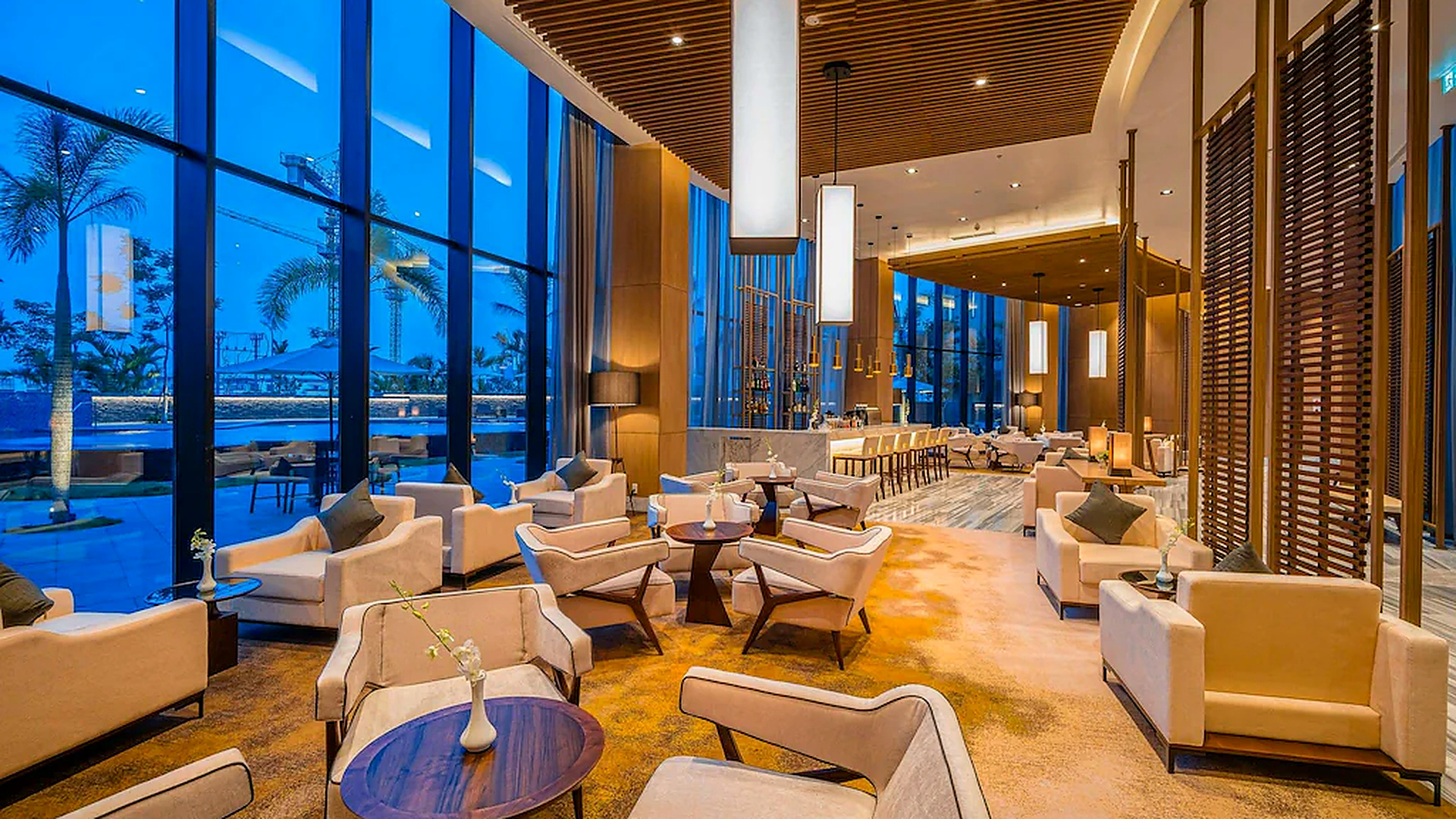 Không gian lounge rộng, trần cao và hệ kính lớn tạo cảm giác sang trọng, thư giãn.