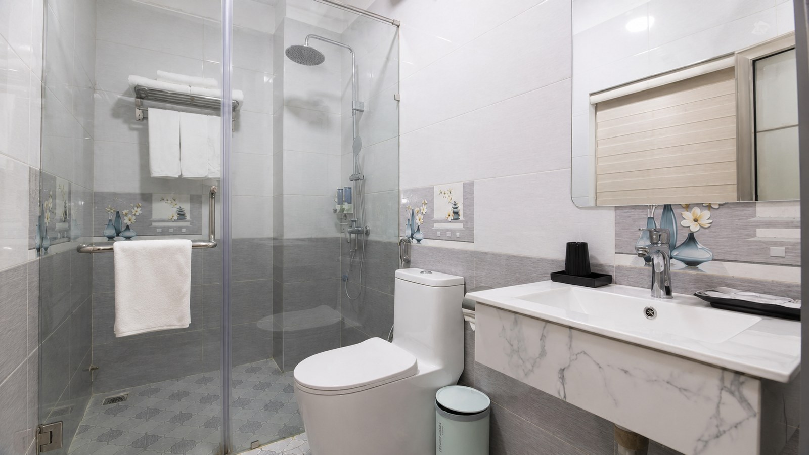 Nội thất phòng tắm khách sạn 3 sao với gạch sáng, khu tắm kính và thiết bị dễ vệ sinh.