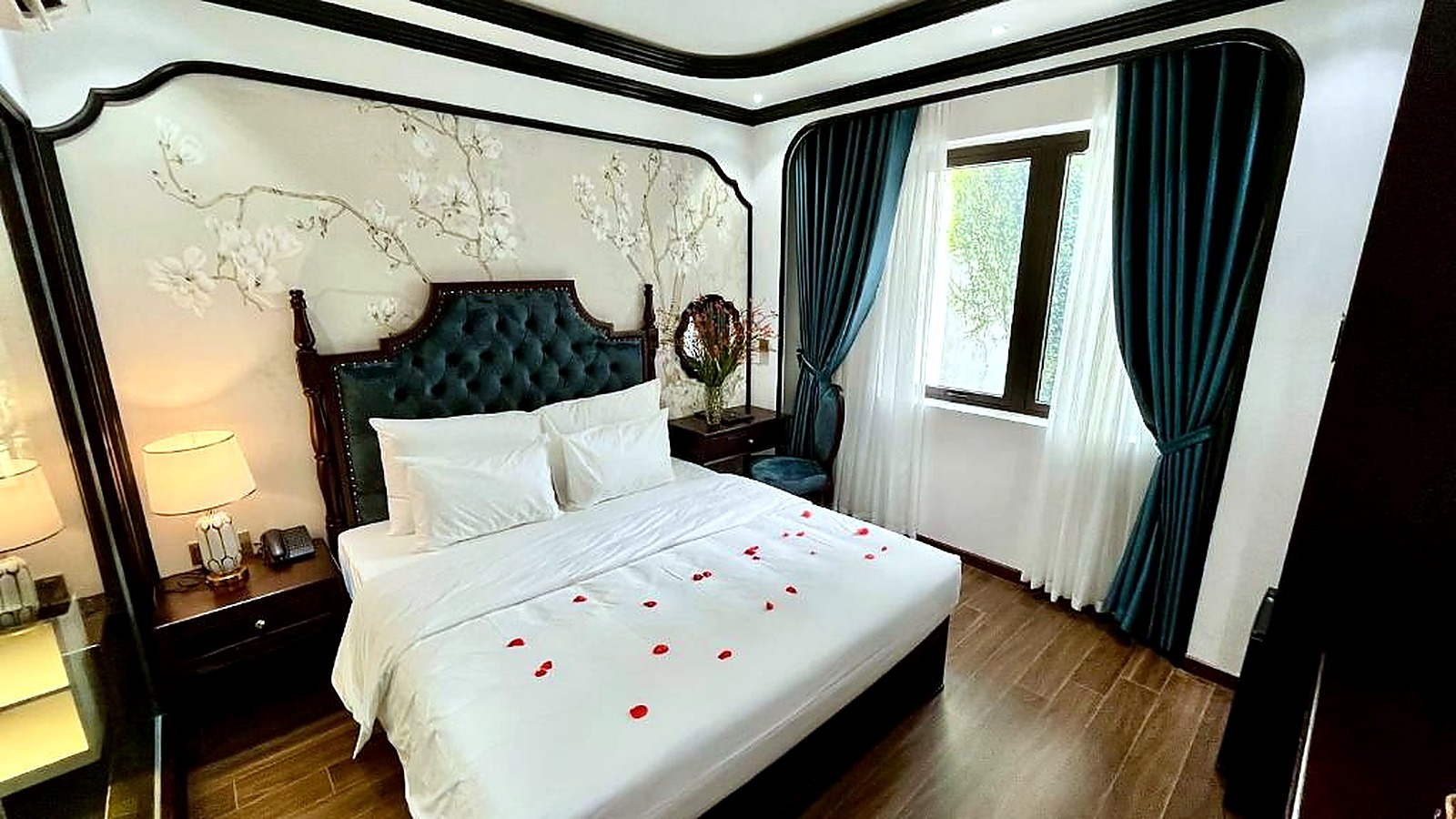 Rèm xanh, đầu giường bọc nỉ và ánh sáng tự nhiên tạo cảm giác nghỉ dưỡng.