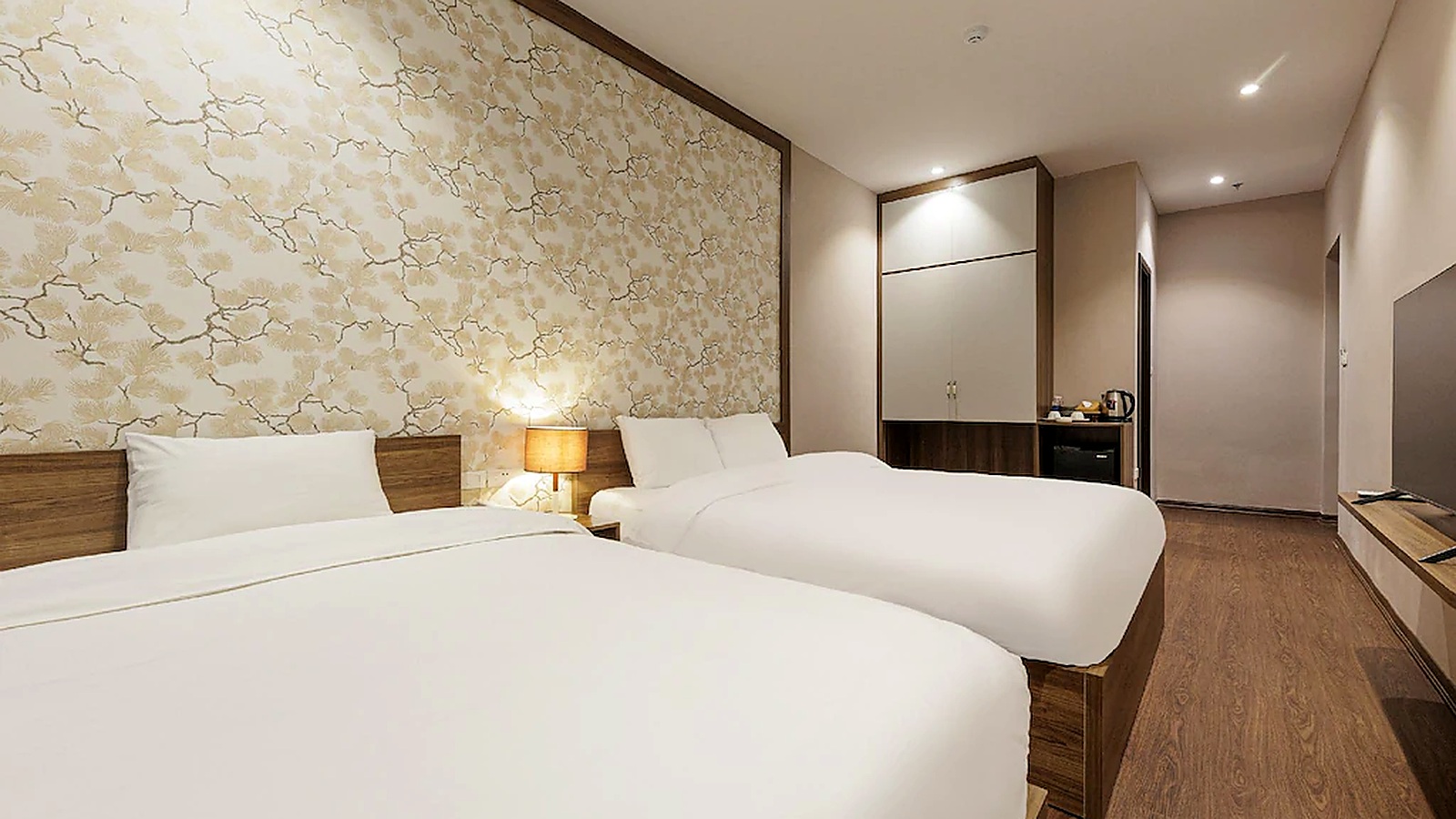 Phòng hai giường rộng hơn với hệ tủ, minibar và lối đi thông thoáng, phù hợp gia đình nhỏ hoặc nhóm khách.