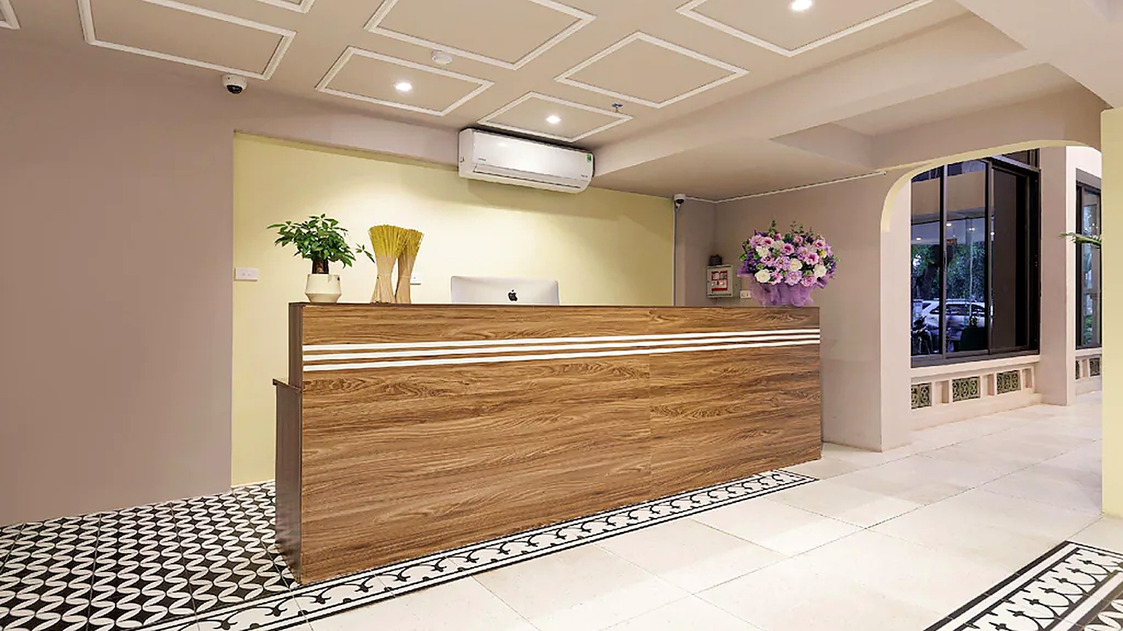 Quầy lễ tân khách sạn 3 sao phong cách hiện đại dùng bề mặt gỗ và đường sáng ngang để tạo cảm giác thân thiện, chuyên nghiệp.