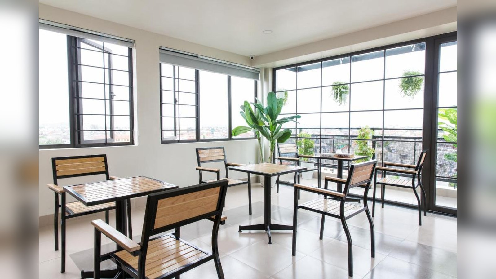 Khu cafe khách sạn 2 sao có cửa kính lớn, cây xanh và view thành phố.