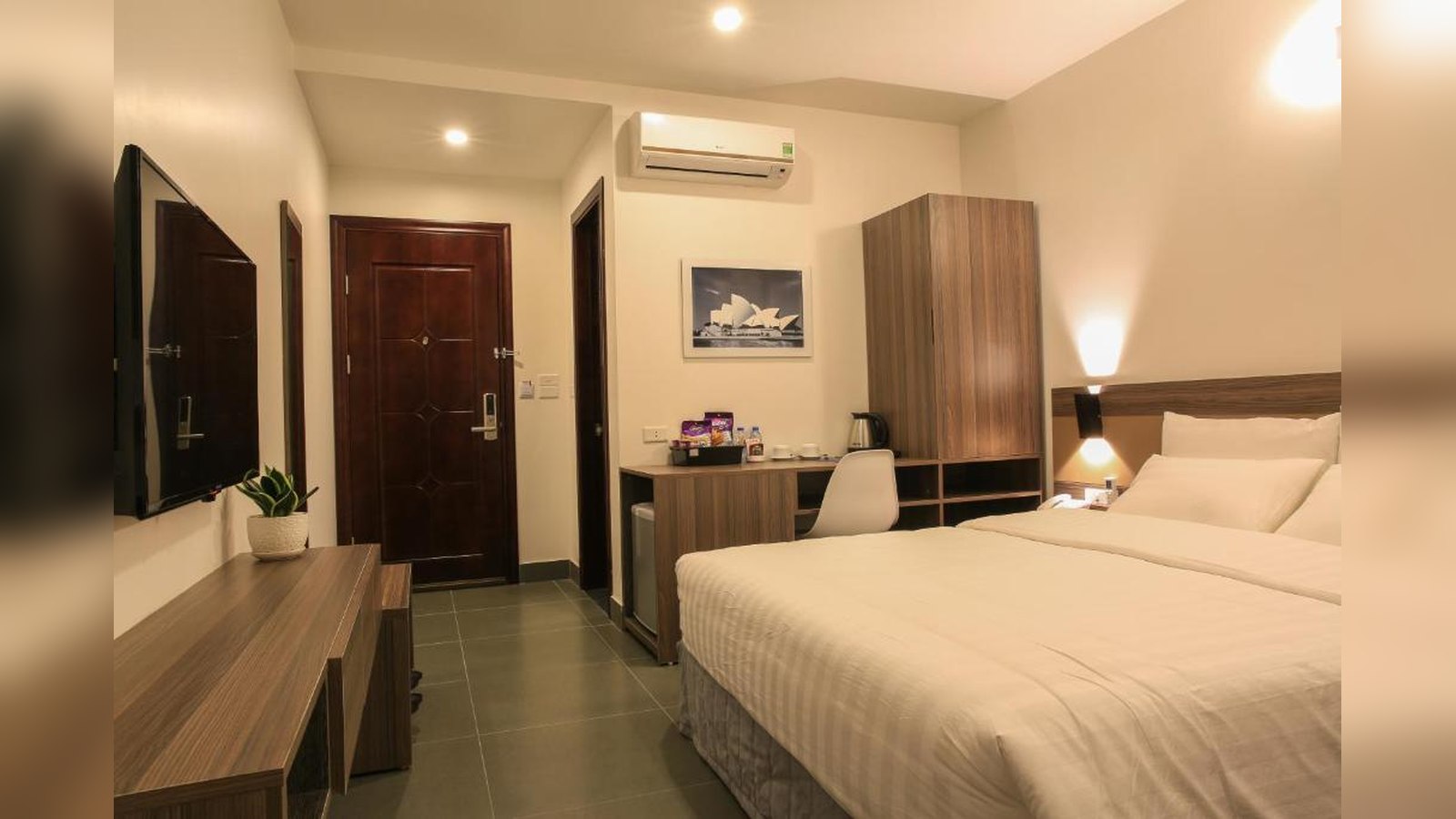 Phòng khách sạn 2 sao tối giản với ánh sáng ấm và hệ tủ gỗ đồng bộ.