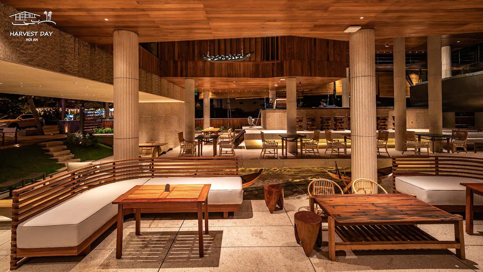 Lounge mở sử dụng trần gỗ, cột đá và các cụm ghế thấp để tạo nhịp nghỉ tự nhiên.