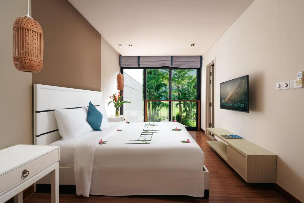 Phòng ngủ dùng nền trắng, gỗ sáng, đèn mây và cửa kính lớn để hướng sự chú ý về mảng xanh bên ngoài.