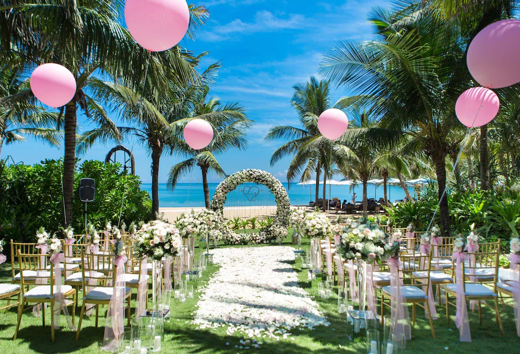 Lối lễ phủ hoa trắng, ghế vàng và đèn lồng hồng tạo một lễ cưới hướng thẳng ra biển.