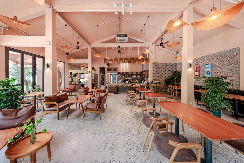 Không gian ăn uống phối terrazzo, gỗ, da nâu và đèn thủ công theo tinh thần Indochine đương đại.