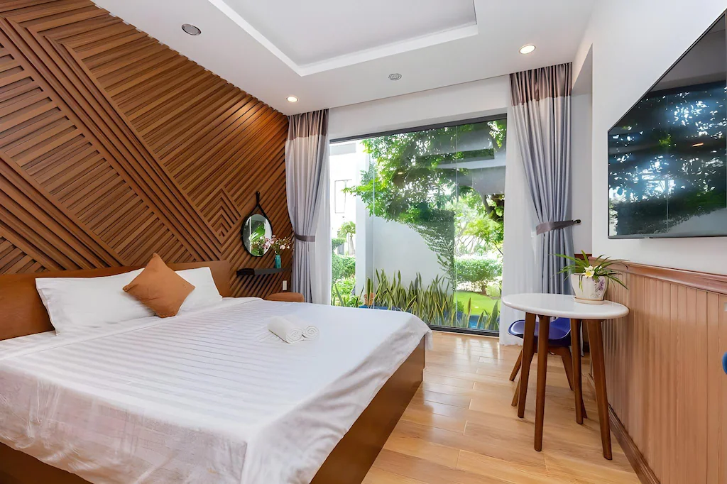 Mảng nan gỗ chéo tạo điểm nhấn ấm áp cho phòng king sáng, gọn và hướng ra khu vườn.