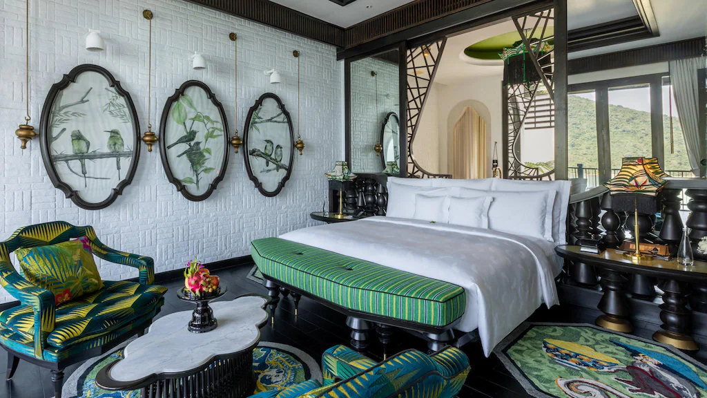 Giường trắng được bao quanh bởi xanh ngọc, đen, vàng và hoa văn lớn trong một căn suite giàu cá tính.