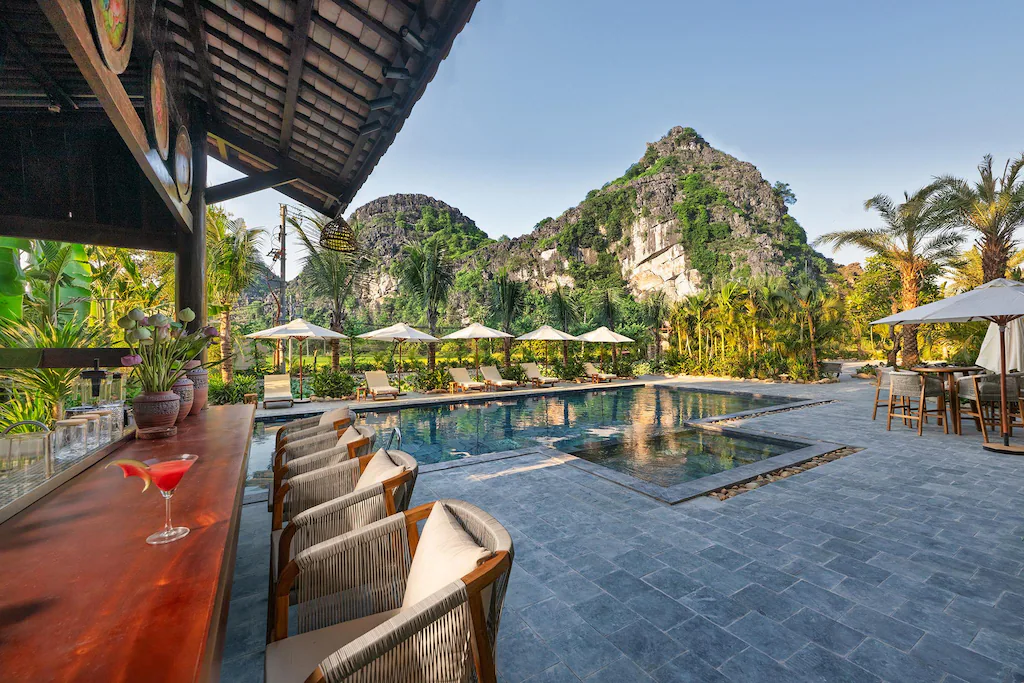 Hồ bơi lát đá tối và quầy bar mở hướng về núi.