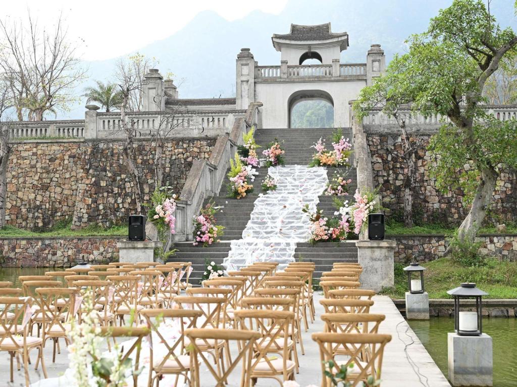 Ghế gỗ và hoa trắng làm nổi kiến trúc cổng đá cùng cảnh quan núi.
