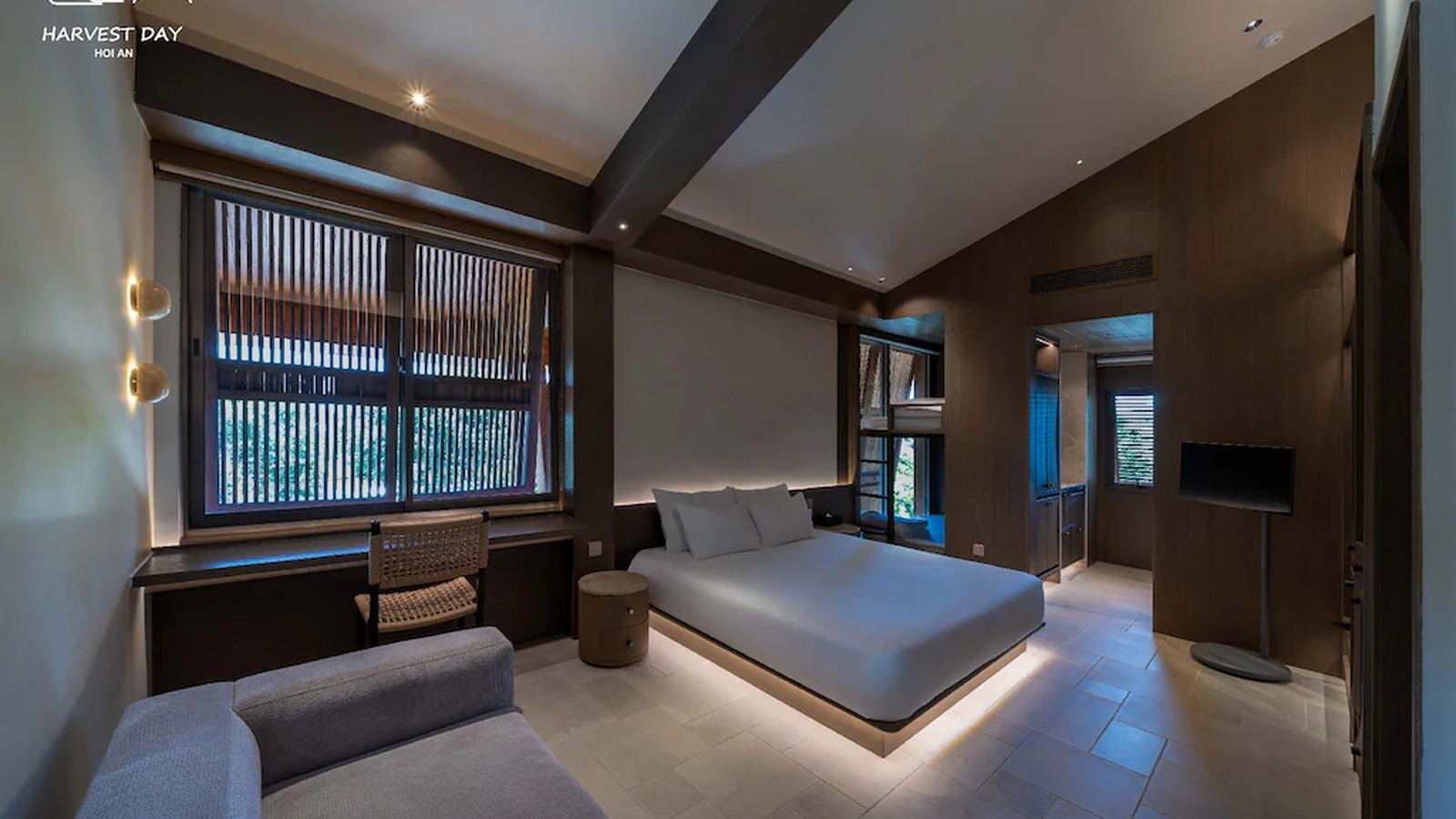 Vách gỗ đậm, sofa thấp và ánh sáng theo lớp tạo một phòng suite kín đáo, ấm áp.