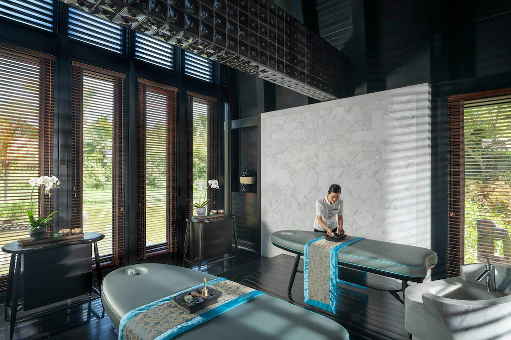 Không gian trị liệu dùng gỗ tối, lam điều tiết sáng và điểm xanh ngọc để tạo cảm giác tĩnh.