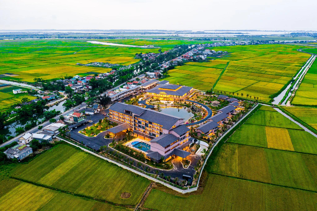 Cụm công trình được tổ chức như một điểm nghỉ thấp thoáng giữa cảnh quan nông nghiệp rộng mở.
