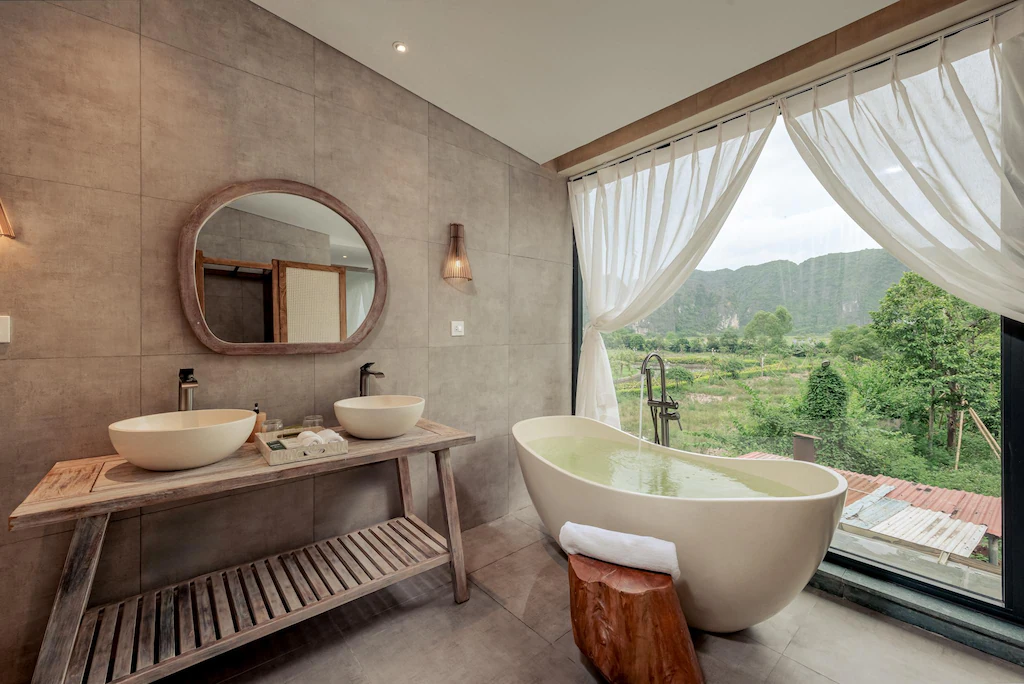 Bồn tắm và lavabo đôi hướng ra cửa kính lớn, nhấn mạnh tiện nghi nghỉ dưỡng hiện đại.