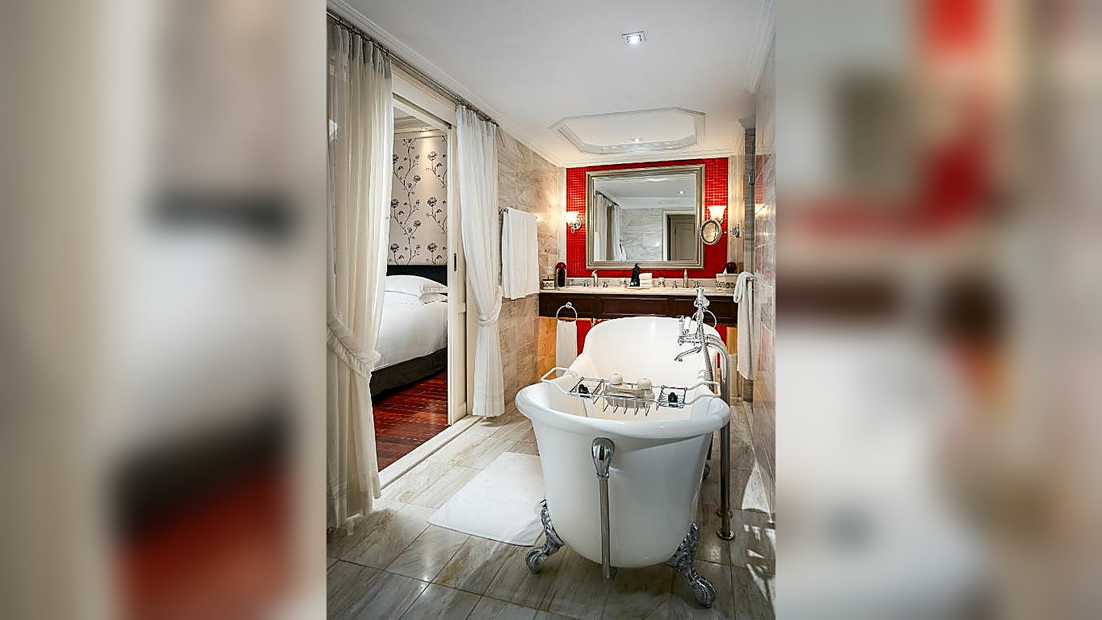 Phòng tắm cao cấp với bồn tắm đặt độc lập, gương lớn và điểm nhấn màu đỏ nổi bật.