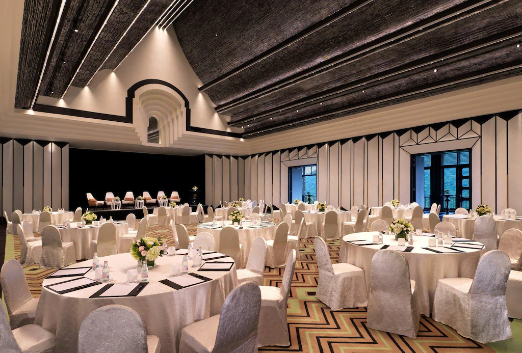 Ballroom dùng bảng màu đen trắng, trần tạo nhịp và bàn tròn cho tiệc cưới hoặc hội nghị lớn.