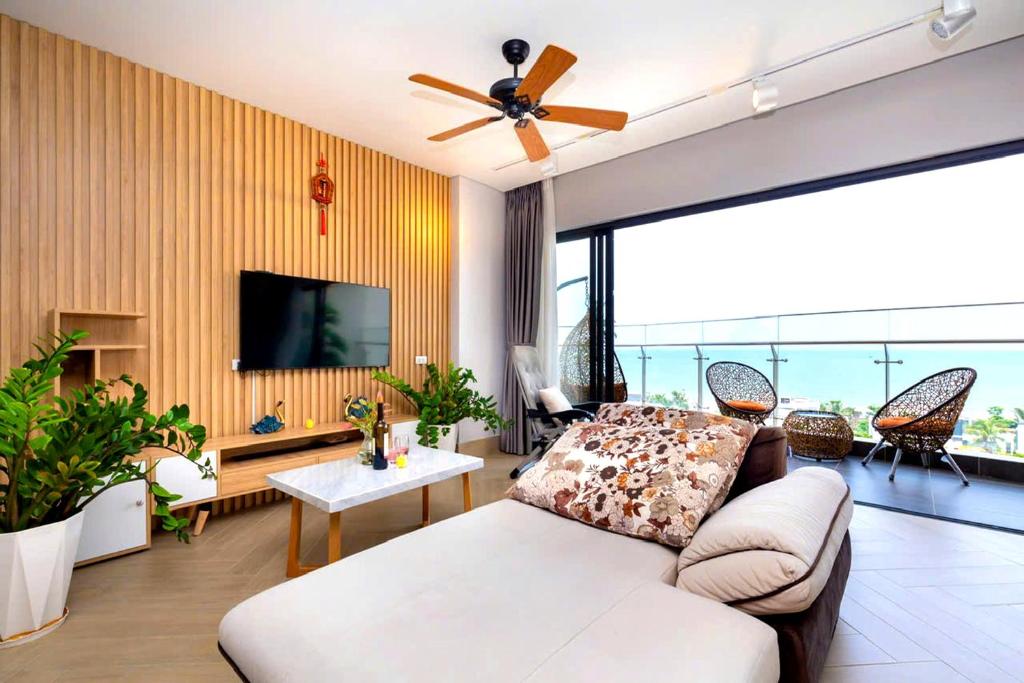 Phòng khách mở ra ban công biển, kết hợp vách nan gỗ, sofa lớn và bảng màu trung tính.