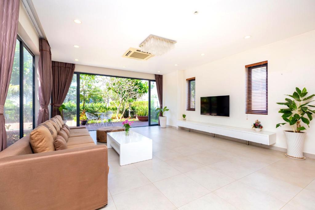 Cửa trượt rộng đưa ánh sáng và màu xanh vào phòng khách tối giản, phù hợp kỳ nghỉ gia đình.