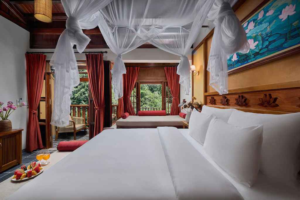 Giường trắng bốn cọc rèm đỏ đất và tranh sen diễn giải nét Đông Dương.