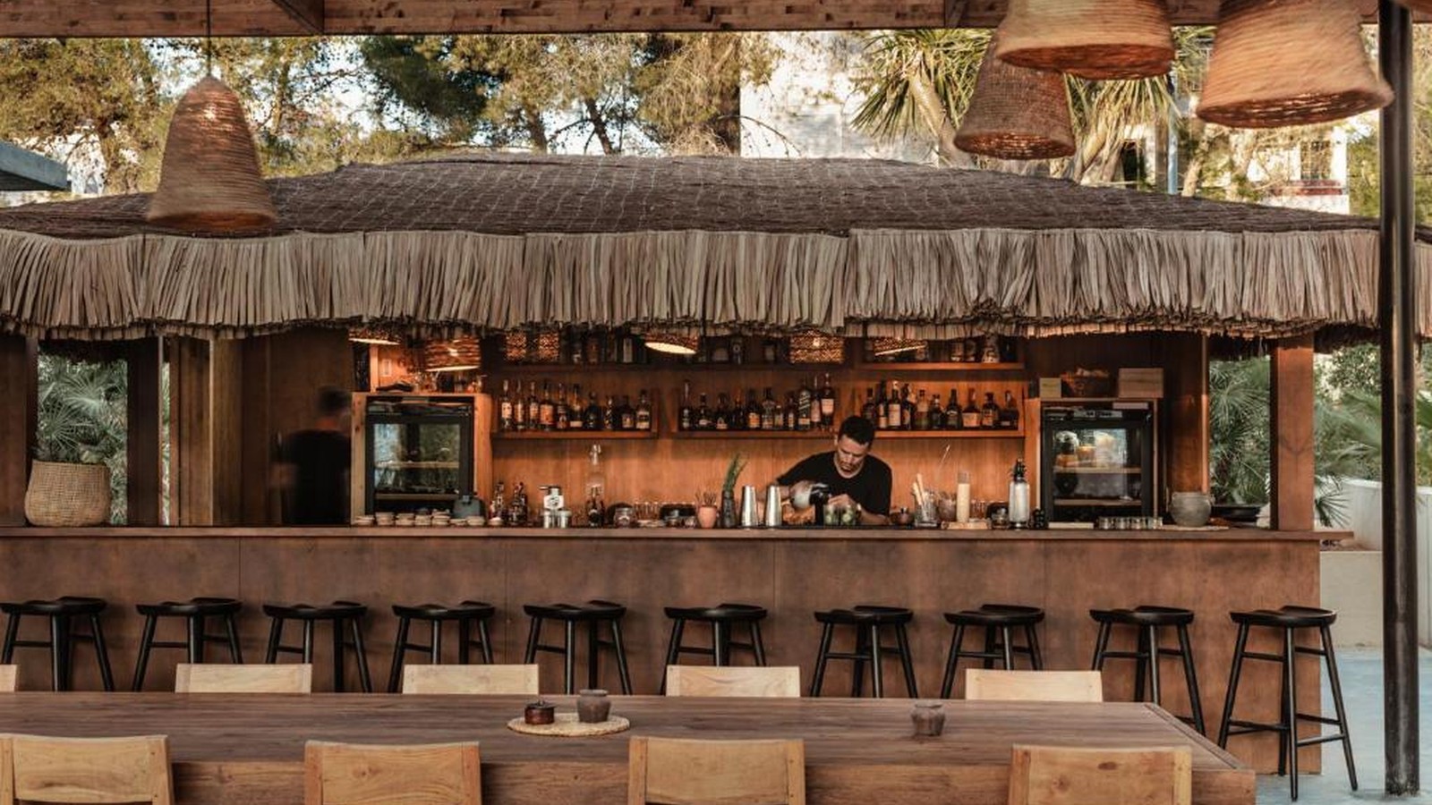 Quầy bar giữ vẻ thủ công của gỗ và mái lá, trong khi ánh sáng ấm tạo bầu không khí thân mật về đêm.