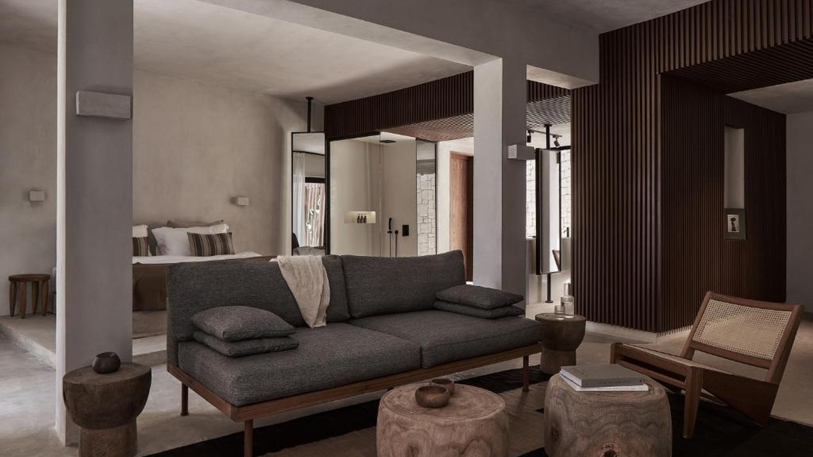 Lounge của suite kết hợp sofa vải thô, ghế mây và bàn gỗ có hình dáng tự nhiên.