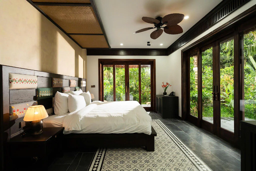 Hai mặt cửa kính lấy sáng và kéo cảnh quan xanh vào phòng, trong khi nội thất giữ bảng màu gỗ tối.