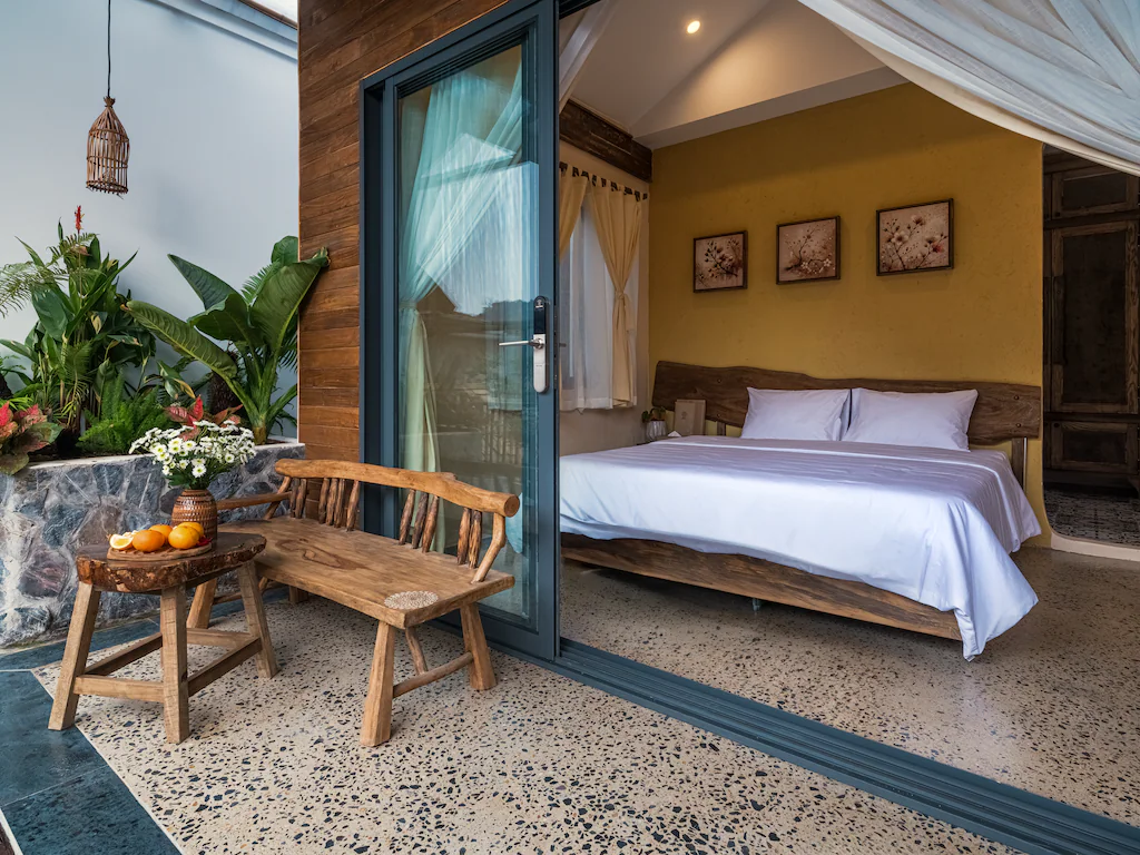 Cửa trượt nối giường ngủ với hiên lát terrazzo và góc ngồi ngoài trời.