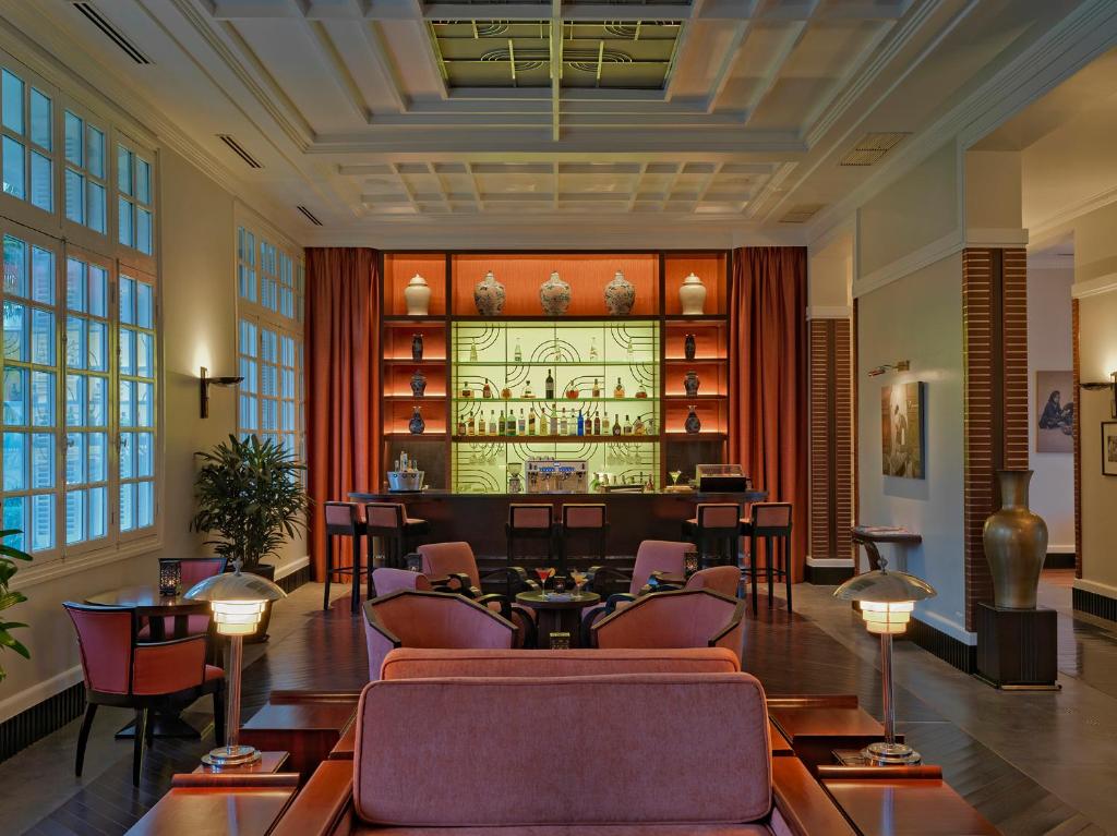 Lounge dùng đồ gỗ tối, sofa đỏ và ánh sáng vàng để tạo một phòng khách lớn giàu ký ức.