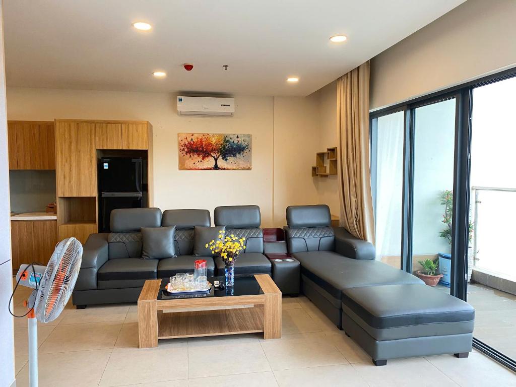Không gian lưu trú dài ngày tích hợp sofa, bàn trà, tủ lạnh và khu bếp gọn cạnh ban công.