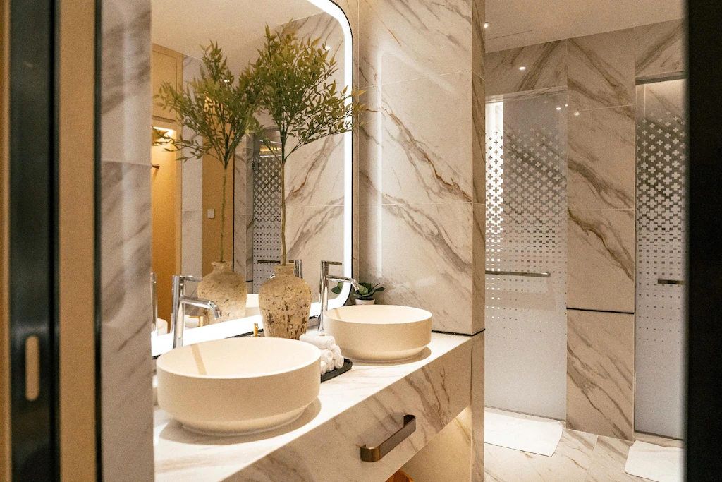 Đá vân sáng, lavabo đôi và vách kính tạo phòng tắm gọn, sáng và sang trọng.