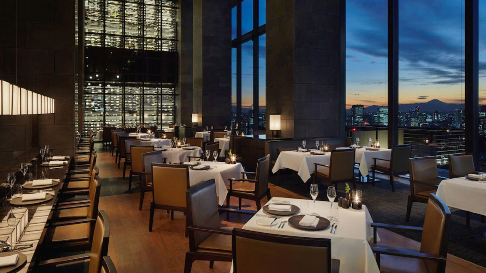 Không gian fine dining cân bằng sự trang trọng của bàn ăn trắng với sắc gỗ trầm và ánh sáng buổi tối.