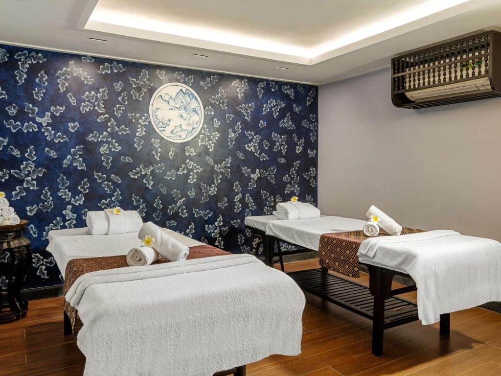 Hai giường trị liệu, họa tiết xanh trắng và ánh sáng trần dịu tạo không gian chăm sóc dành cho hai người.