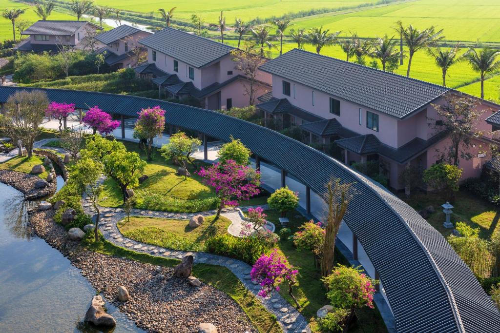 Các villa mái dốc nép quanh vườn, mặt nước và cầu cong tạo hành trình đi bộ chậm.