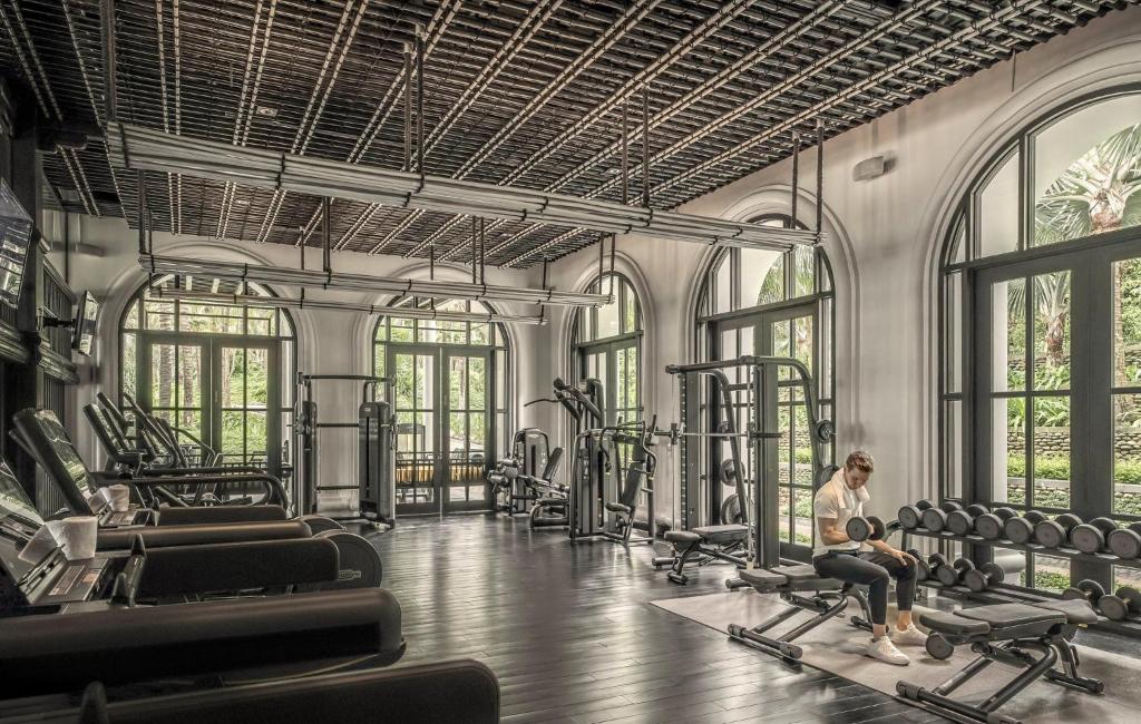 Khu gym dùng trần nan, khung cửa vòm và ánh sáng vườn để giảm cảm giác của một phòng máy kín.