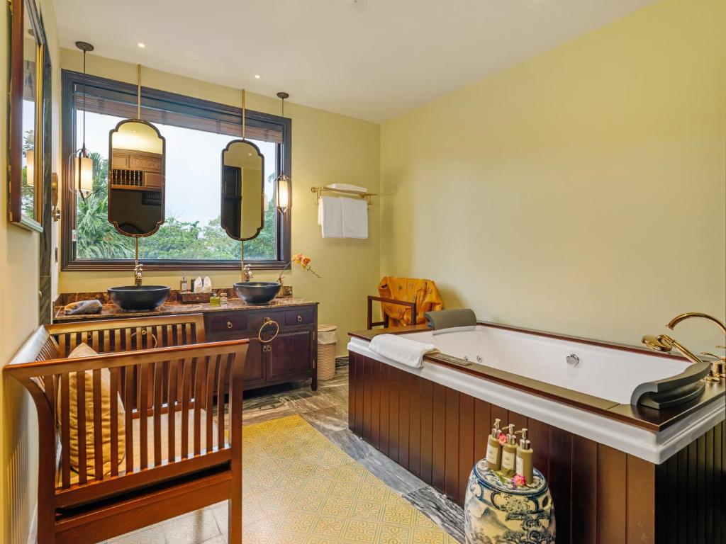 Bồn ngâm dài, bàn gỗ, ghế mây và đèn thả tạo một nghi thức tắm thư giãn giàu chất thủ công.