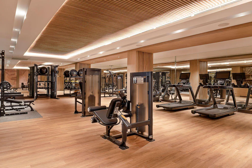Máy chạy bộ, khu tạ và gương lớn được bố trí rõ trong phòng gym sáng, rộng.