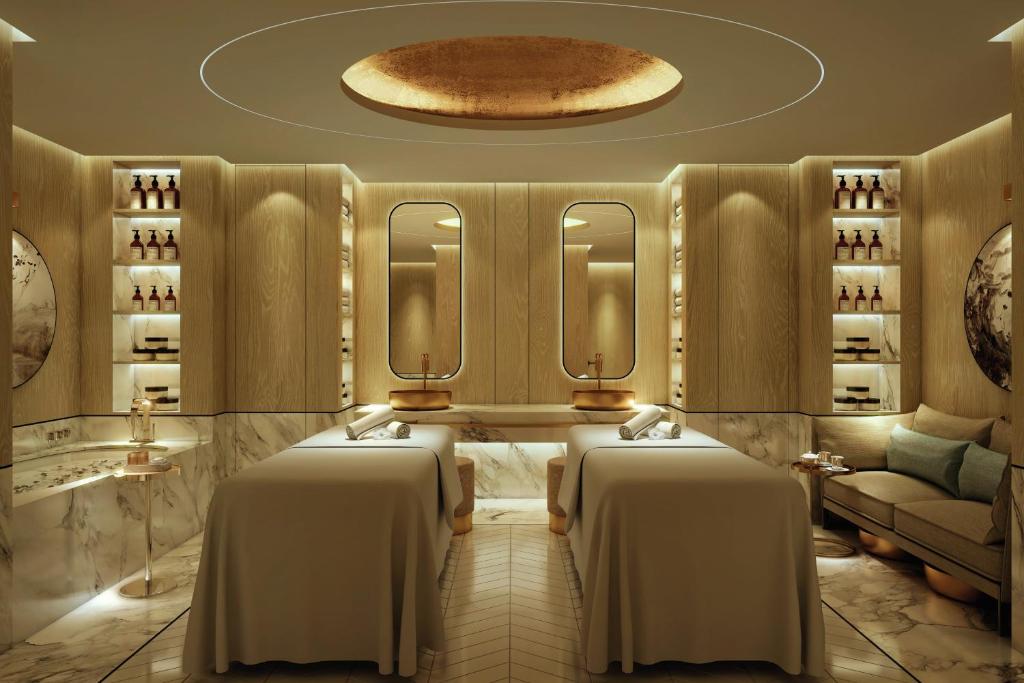 Phòng spa đôi dùng đá sáng, gỗ, hốc trưng bày và ánh sáng dịu để tạo sự riêng tư.