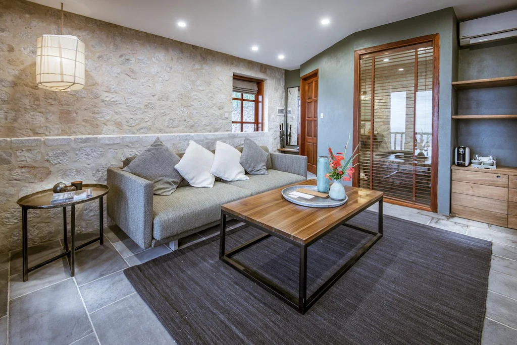 Sofa vải, bàn gỗ chân thép và minibar âm tường tạo một phòng khách sử dụng được thật cho kỳ nghỉ dài.
