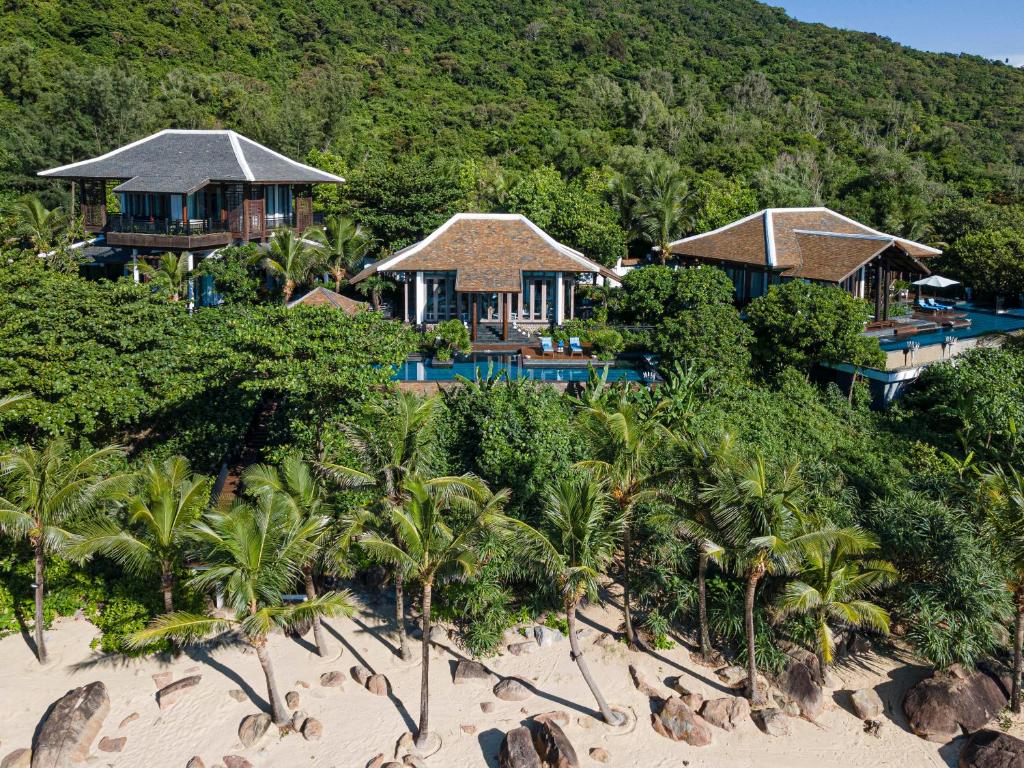Những villa mái dốc xen trong tán cây, mỗi khối có khoảng hiên và mặt nước hướng ra biển.