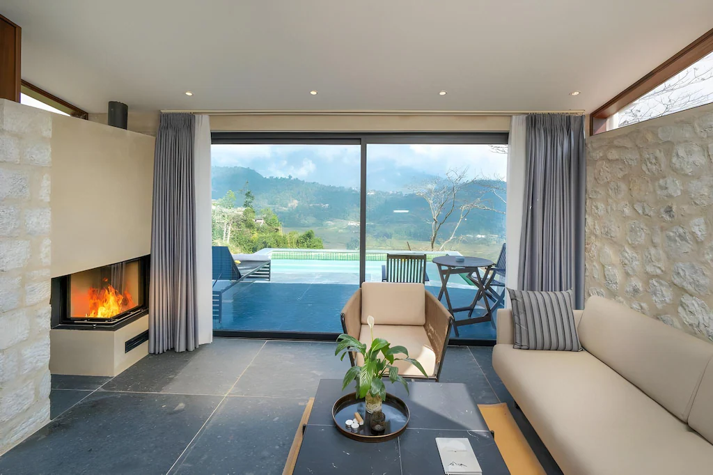 Lò sưởi đặt đối diện sofa, trong khi cửa trượt mở phòng khách về phía mặt nước và thung lũng.